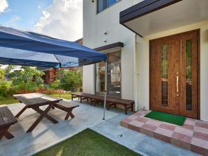 a patio with benches and a blue umbrella at The Pool Resort Villa Hasta Manana in Onna