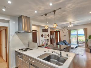 a kitchen with a sink and a living room at The Pool Resort Villa Hasta Manana in Onna