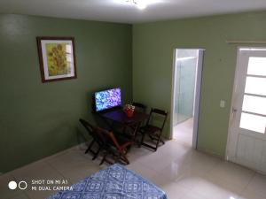 um quarto com uma mesa e cadeiras e um quarto com paredes verdes em Apartamento NA PRAIA, 2 suites com cozinha em Ilhéus