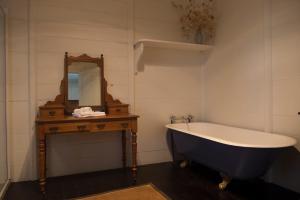 ein Badezimmer mit einer Badewanne und einem Spiegel auf dem Tisch in der Unterkunft Hillview Heritage Estate in Sutton Forest