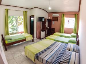 una camera d'albergo con tre letti e una tv di Pousada Manga Rosa- Arraial a Arraial d'Ajuda Altre 63 foto