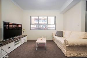 a living room with a couch and a flat screen tv at The Happy Delightful Place - Entire 2 Room Apartment in Cockburn Central