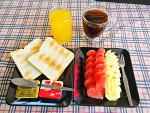 a plate of food with fruit and bread and a glass of juice at Sleep In Lanta Resort in Ko Lanta