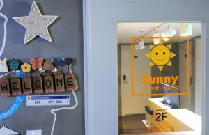 a hallway with a door with a smiley sign and a star at Sunny Guesthouse Seoul City in Seoul