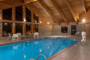 Una piscina con sillas y mesas en un edificio. en AmericInn by Wyndham Coralville, en Coralville