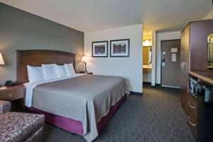 a hotel room with a large bed and a television at AmericInn by Wyndham Grundy Center in Grundy Center +13 photos