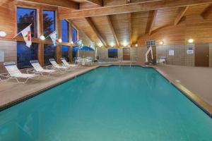 a large swimming pool in a building with chairs at AmericInn by Wyndham Webster City in Webster City