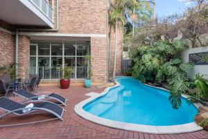 a swimming pool in front of a house with two lounge chairs at Nesuto Pennant Hills in Pennant Hills