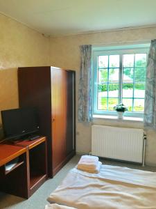 Schlafzimmer mit einem Bett, einem TV und einem Fenster in der Unterkunft Abild Kro & Hotel in Tønder