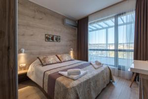 a bedroom with a bed and a large window at City Apartments Triumph in Varna City
