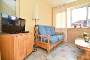 a living room with a blue chair and a television at Comfort Inn Old Town in Budva
