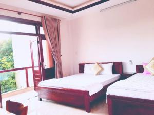 une chambre avec deux lits et une grande fenêtre dans l'établissement Dream Flower Homestay, à Hội An