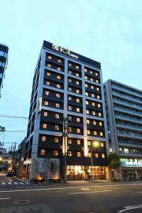 um edifício alto com um sinal em cima em ICI HOTEL Ueno Shin Okachimachi em Tóquio