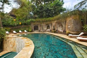 a swimming pool with chaise lounges and chairs around it at Ibah in Ubud
