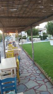 a patio with tables and chairs and a grass field at Andy's Gardens in Gerani