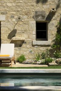 un edificio de piedra con un banco junto a una piscina en Les Bastides du Mas de l'Amarine, en Saint-Rémy-de-Provence