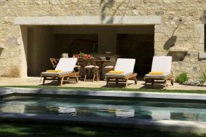 two chairs and a table next to a swimming pool at Les Bastides du Mas de l'Amarine in Saint-Rémy-de-Provence