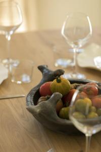 un bol de fruta en una mesa con copas de vino en Les Bastides du Mas de l'Amarine, en Saint-Rémy-de-Provence