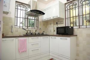 a kitchen with white cabinets and a sink and windows at Villino Kalipparambil in Ernakulam