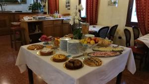 LegnaroにあるHotel AB Barettaの白いテーブル布の上に食べ物が詰まったテーブル