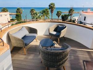 un balcón con sillas y mesas de mimbre y el océano en Casa Acacia Mar, en Cambrils