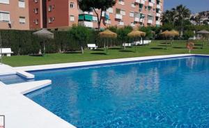 a large blue swimming pool in front of a building at Apto PLAYA LA CALA in front of the beach Free parking in Málaga