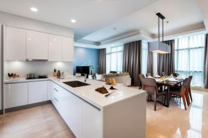 a kitchen and dining room with white cabinets and a table at Oakwood Suites La Maison Jakarta in Jakarta