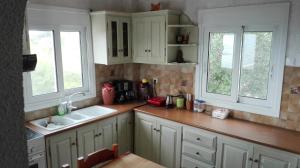 a kitchen with white cabinets and a sink and two windows at Villa Karla in Pefkali