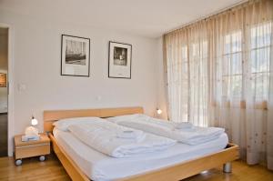 1 dormitorio con 1 cama grande con sábanas blancas en Apartment Atlanta - GRIWA RENT AG, en Grindelwald