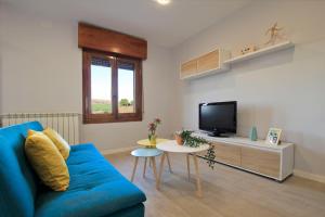 a living room with a blue couch and a tv at Mirador de Cervantes in Toledo