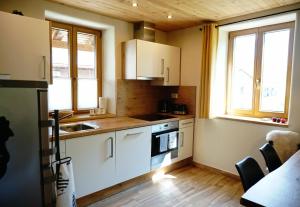 a kitchen with white cabinets and a sink and two windows at ecoHouse FURLAN - Apartment PINJA in Kobarid