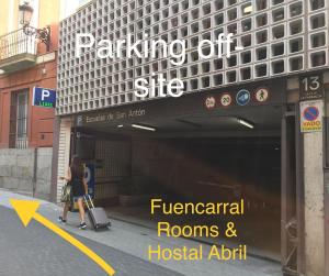 una mujer saliendo de un edificio con su equipaje en Fuencarral Rooms, en Madrid