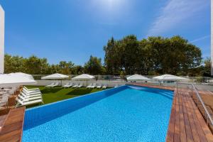 una piscina con tumbonas y sombrillas en Lux Fatima Park - Hotel, Suites & Residence en Fátima