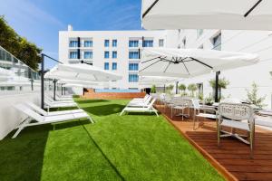 a deck with white chairs and tables and umbrellas at Lux Fatima Park - Hotel, Suites & Residence in Fátima