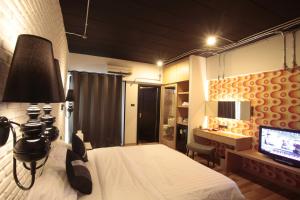 sypialnia z łóżkiem, biurkiem i telewizorem w obiekcie Diary Suite w mieście Nakhon Pathom