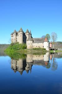 un castillo reflejo en un cuerpo de agua en Chateau De Val, en Lanobre