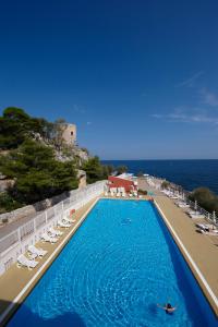 une grande piscine avec des chaises longues et l'océan dans l'établissement Splendid Hotel La Torre, à Mondello