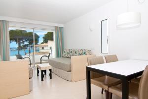 Sala de estar con cama y mesa de comedor en Hoposa Pollensamar Apartamentos, en Puerto Pollensa