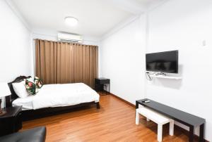 ein Hotelzimmer mit einem Bett und einem Fernseher in der Unterkunft House of Happiness in Bangkok