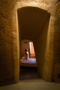 eine Person, die in einem Tunnel auf einem Bett sitzt in der Unterkunft San Giovanni Vecchio - Residenza in Matera