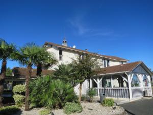 una casa blanca con palmeras delante en Hotel Wood Inn Bordeaux Aéroport en Mérignac