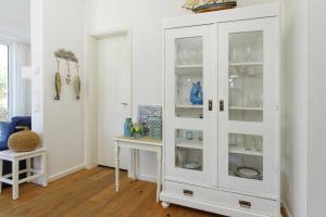 a white cabinet with glass doors in a room at Kapitaensweg 4 Koje 03 in Karlshagen