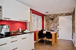 cocina con paredes rojas y mesa con sillas en Apartment Felix - GRIWA RENT AG en Grindelwald