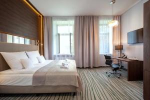 a hotel room with a large bed and a desk at Plaza Boutique Hotel in Kraków