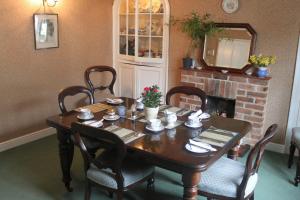 a dining room table with chairs and a fireplace at IVY COTTAGE B and B in Buckingham