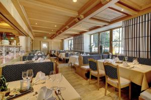 a restaurant with white tables and chairs and windows at Wellnesshotel Hofbräuhaus in Bodenmais