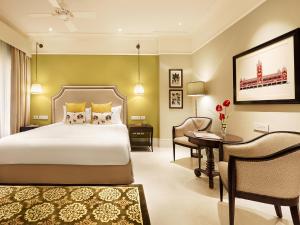 a bedroom with a bed and a desk and a chair at Taj Connemara, Chennai in Chennai