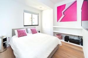 a bedroom with a white bed with pink pillows at Frishman Dream by Five Stay in Tel Aviv