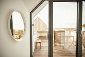 a room with a mirror and a balcony with chairs at Villa Azure I in Fehmarn