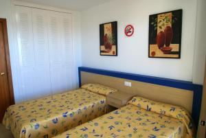 ベニドルムにあるApartamentos Paraiso 10のベッドルーム1室(ベッド2台付)が備わります。壁に2枚の写真が飾られています。